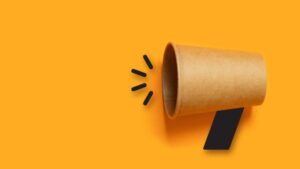 Business concept image with paper cup megaphone on orange background with copy space. Attention concept announcement.