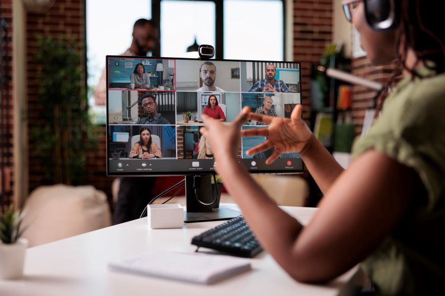 Employee working from home gesturing in video conference with colleagues at desk