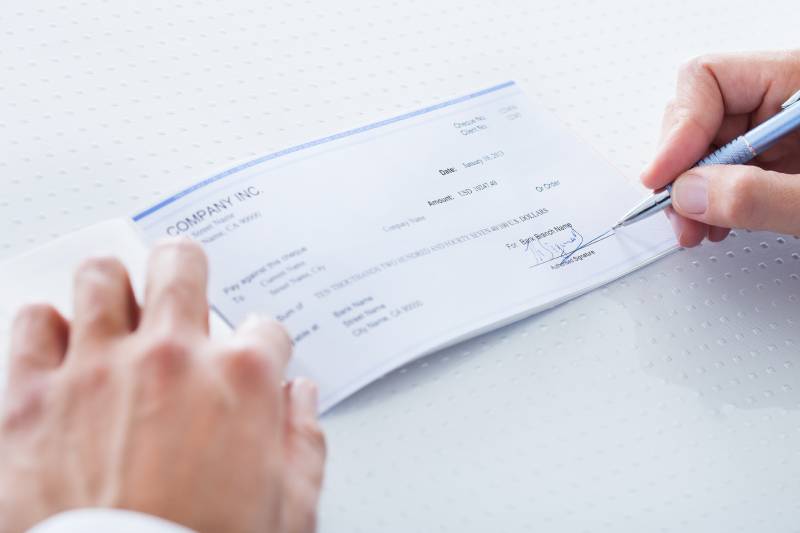 Close-up of hand filling cheque.