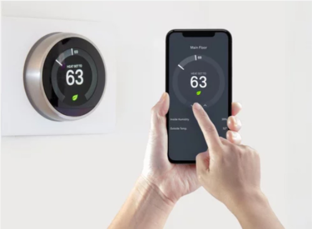 A person using a smartphone app to control a wireless smart thermostat.
