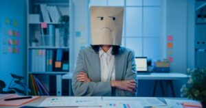A disgruntled employee wearing a paper bag over their head to symbolize a negative mood, conveying the concept of an employee with a challenging attitude.