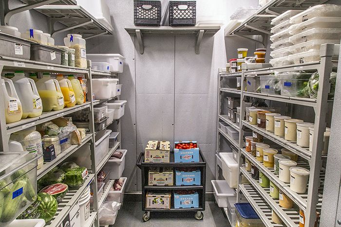 Well-organized walk-in storage lined with plastic containers and ingredients.
