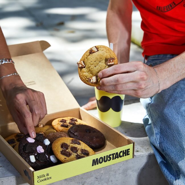Moustache Cookies ' packaging design featuring its logo and brand color scheme,