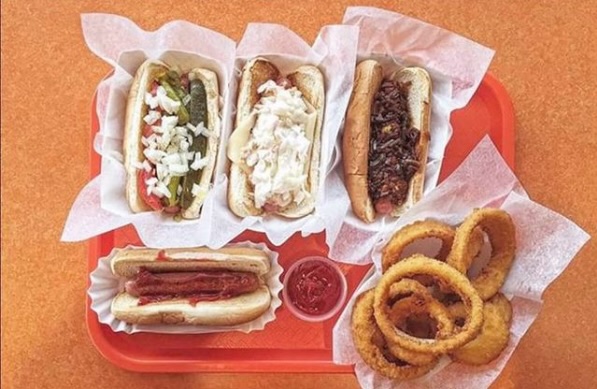 A tray of four hot dogs and a side of onion rings.