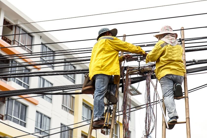 Workers on a ladder repairing cable lines.