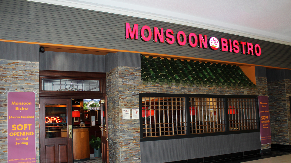 Monsoon Bistro restaurant with a soft opening poster by its entrance