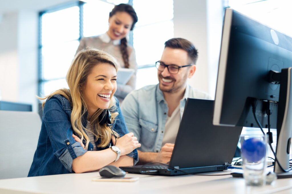 Smiling coworkers training together on a computer