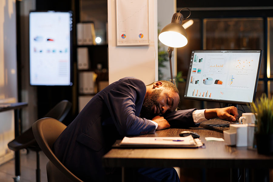 Tired executive worker sleeping on desk in startup office.