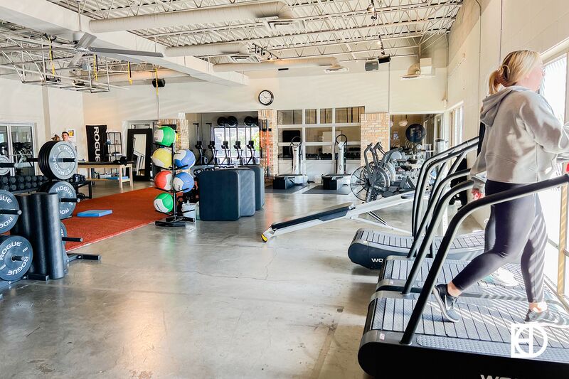 Fit Flex Fly gym with workout equipment and machines and person walking on treadmill.