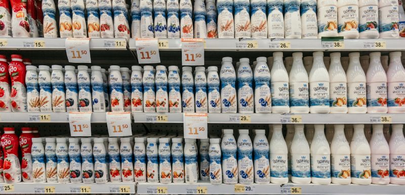 Bottles of milk on supermarket shelves with price tags.