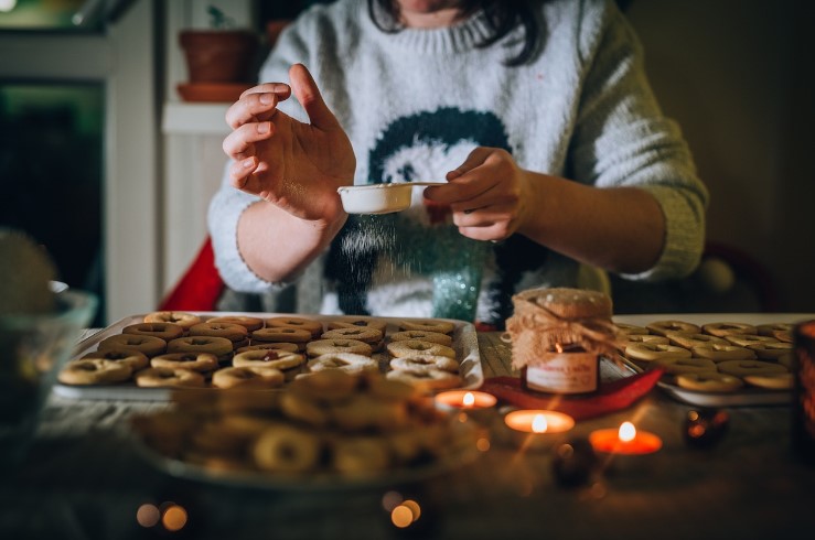 Woman dusting baked cookies with sugar