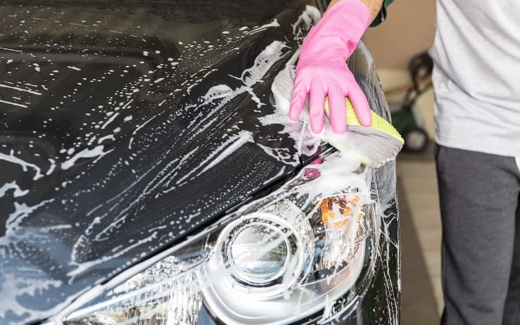 Man in rubber gloves washing car