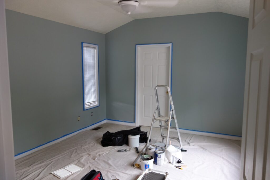 Picture of home being painted with a ladder and painting supplies.