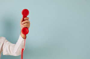 Man hand isolated on green studio background hold corded telephone for call.