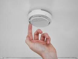 picture of a hand reaching for a fire alarm