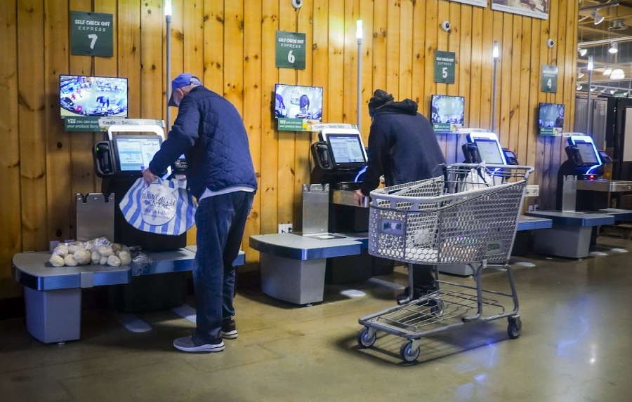 Two men paying in the self-checkout counters.