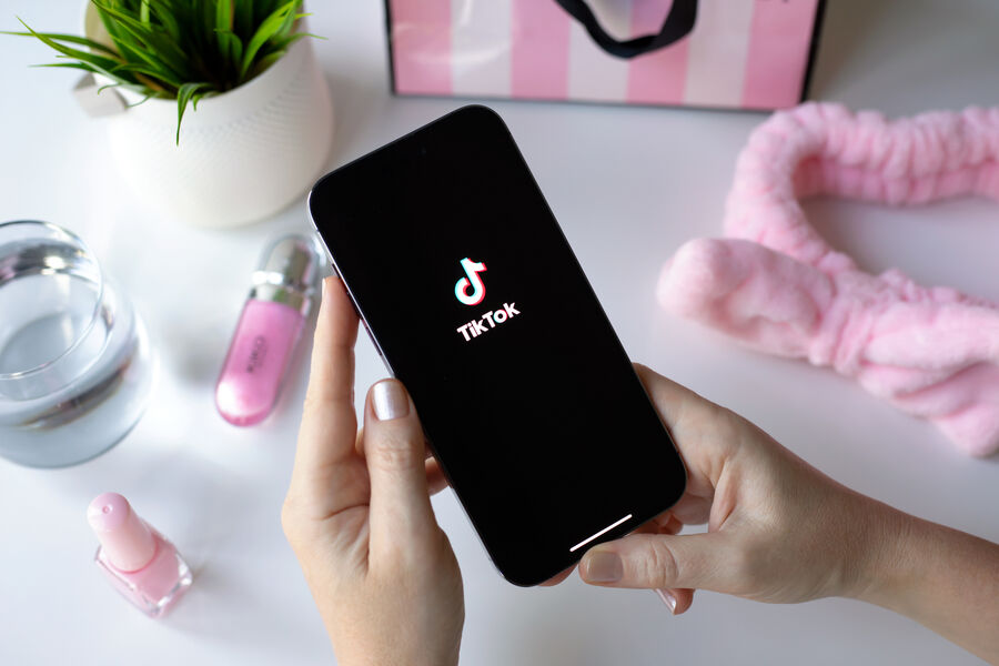 A woman holding a phone with TikTok logo on display.