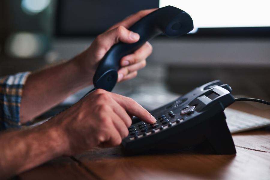 A man dialing a number on a landline.