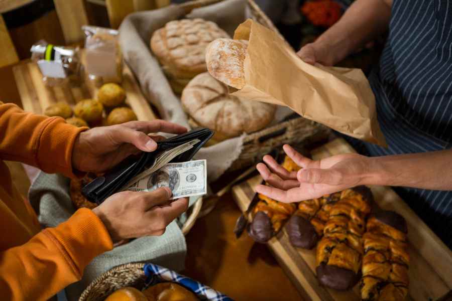 Customer paying bill by cash at bread counter.