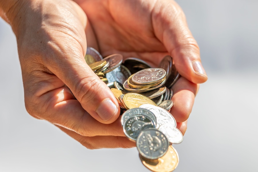 Closeup shot of two hands full of Canadian cash coins and dropping them. Depreciation concept.