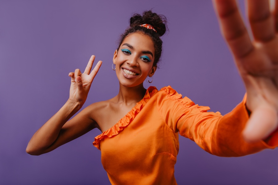 Fascinating girl with blue makeup making selfie with smile. Indoor shot of fashionable lady.