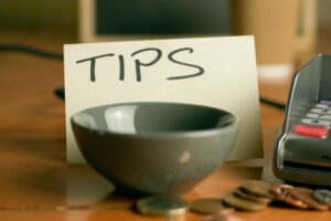 Closeup shot of a bowl near a contactless pdq machine and a tips note leaning on a coffee cup.