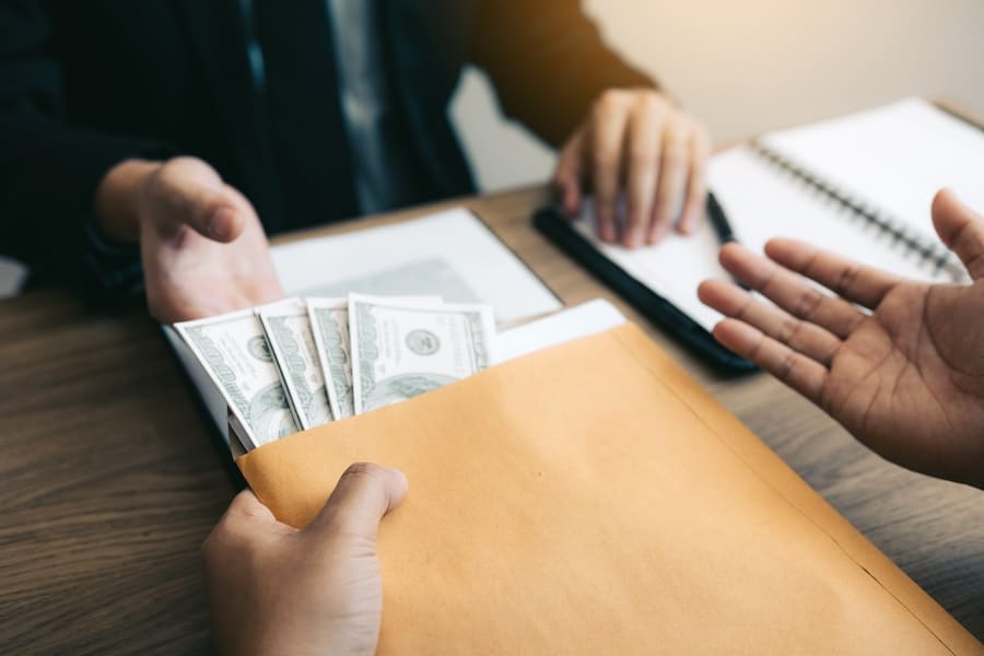 A person holding an envelope filled with cash, ready to hand it over to someone.