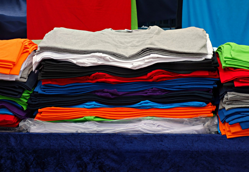 A stack of shirts of various colors in a store.