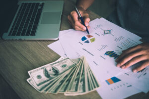 Working place of trader. The table covered by cash notes, keyboard and financial charts.