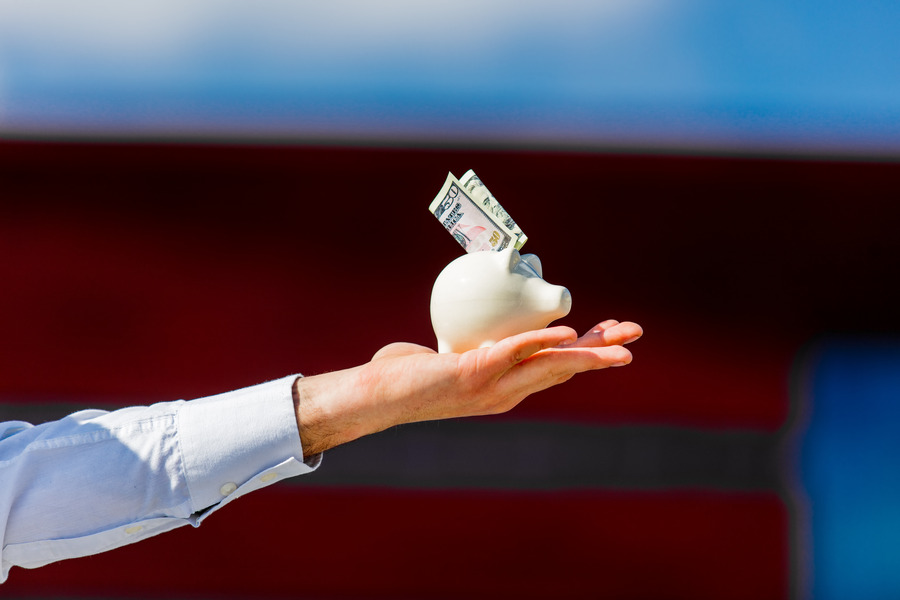 male hand holding piggy bank with cash dollars