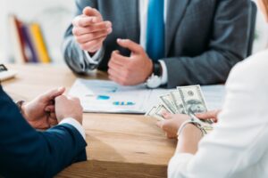 Selective focus of investor holding money with colleagues at office.