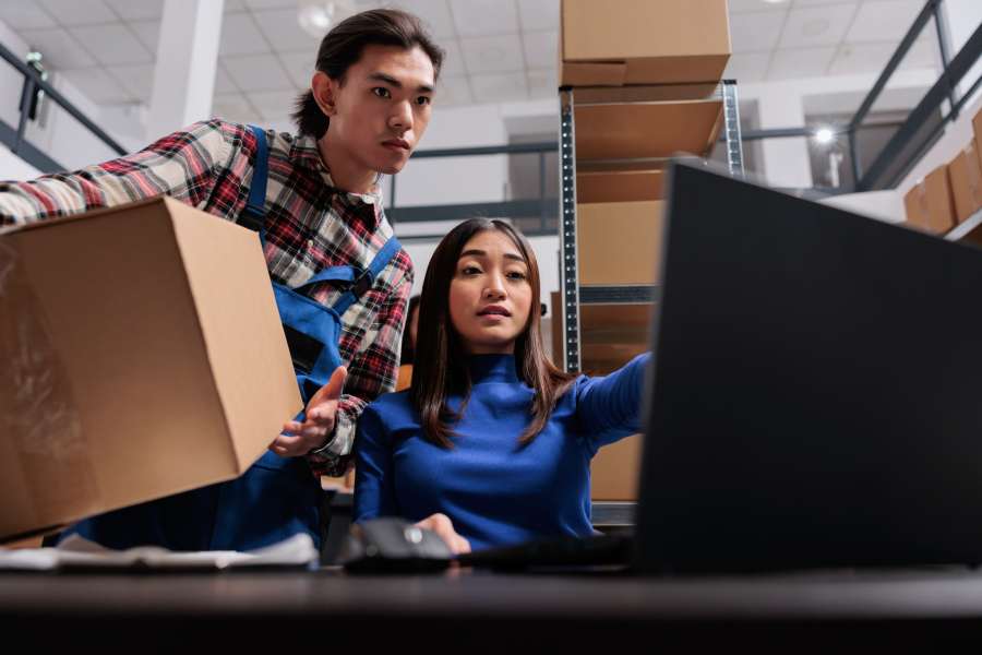 Post office warehouse asian workers preparing package for dispatching.