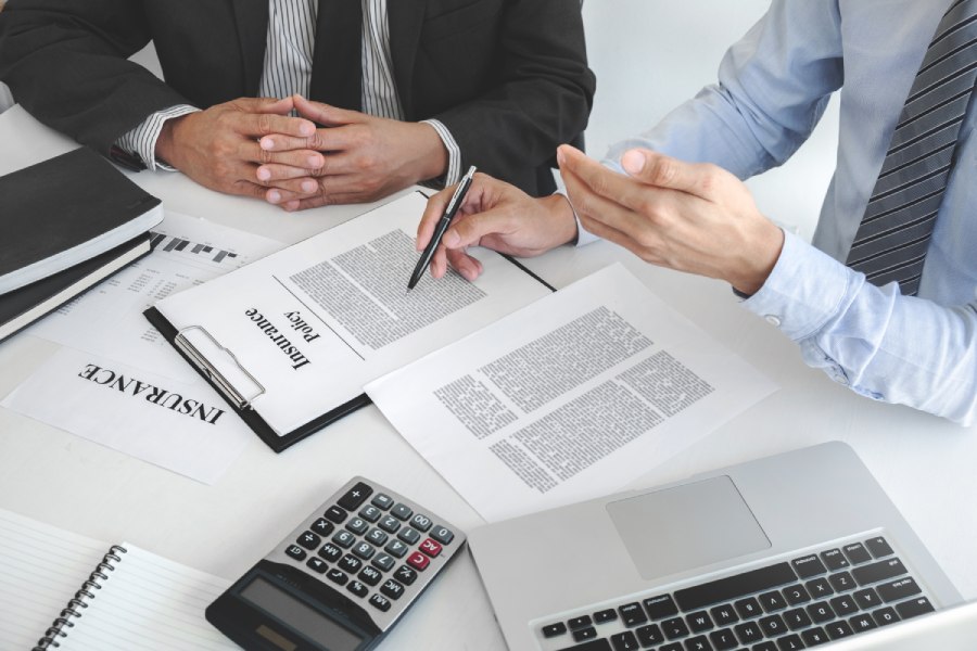 Insurance agent explaining insurance policy to customer in office room.