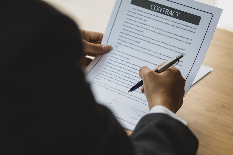 A lawyer working in the office reading documents and signing legal agreement contracts.