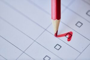 A red pencil writing a checkmark inside a check box.
