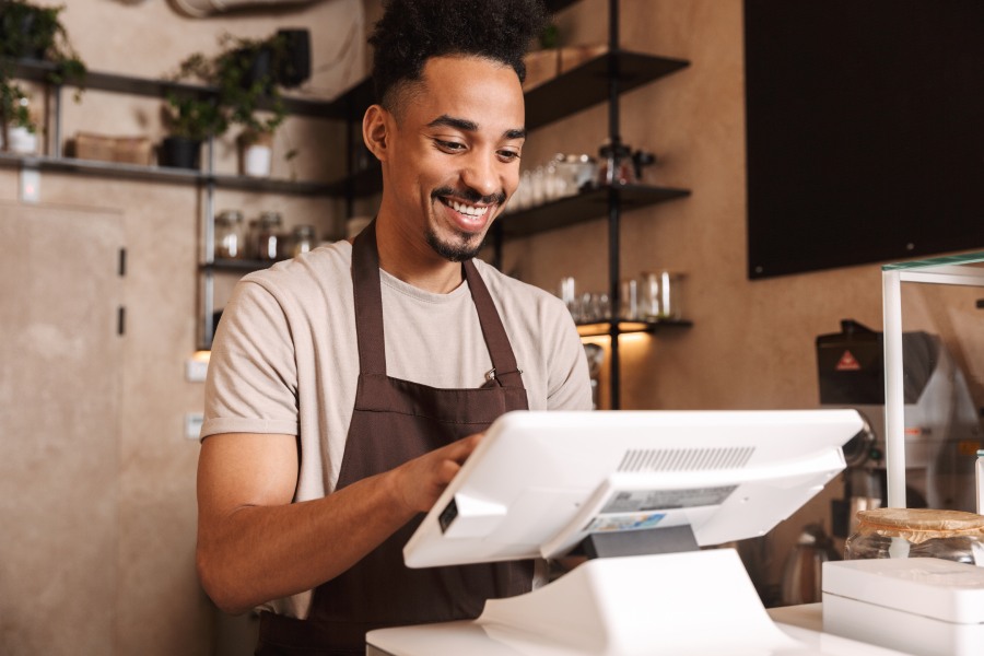 A smiling restaurant cashier accepting order through CRM platform.