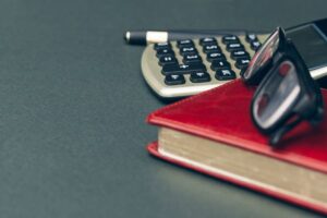 Accounting book with calculator on table in office