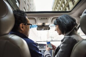 A young woman and young man in a car looking at a map on the display of a cellphone,