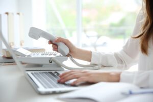 Businesswoman with office IP telephone.