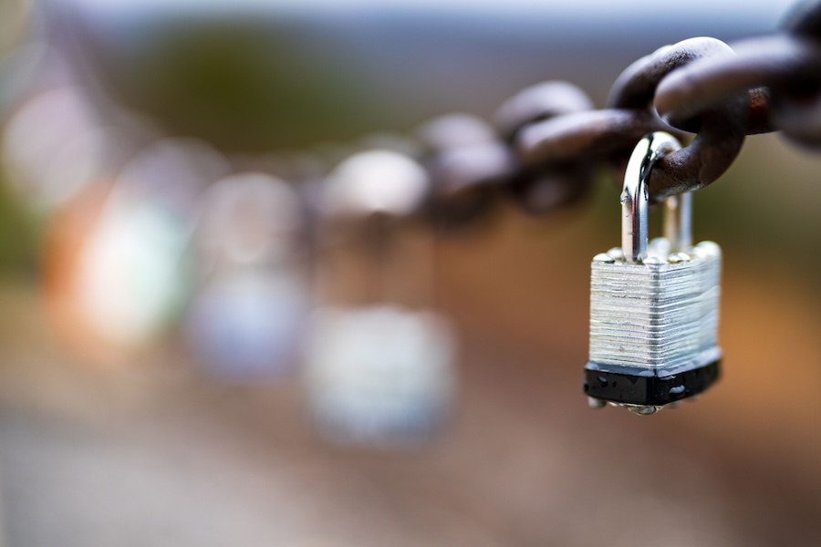 Selective focus shot of an old rusty chain with a padlock secured to it.