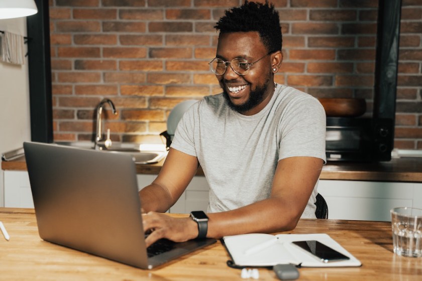 Man working on laptop at a kitchen table.