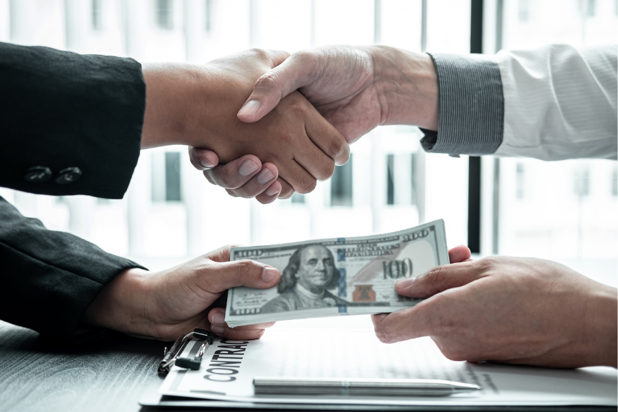 Business people shaking hands with money in hands from partner