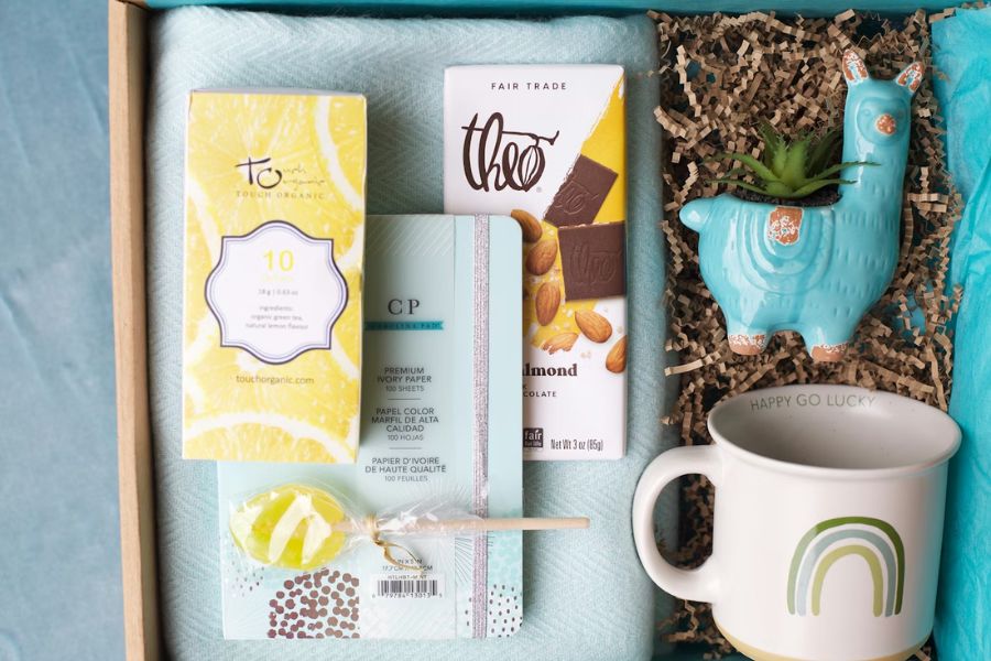 Subscription box with a mug, chocolates, paper, candy and a ceramic llama figurine