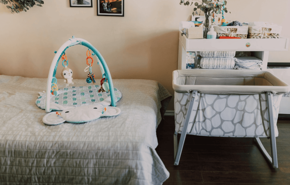 Baby bassinet, play mat, and changing station in a nursery, gently used baby gear that can be resold locally for profit