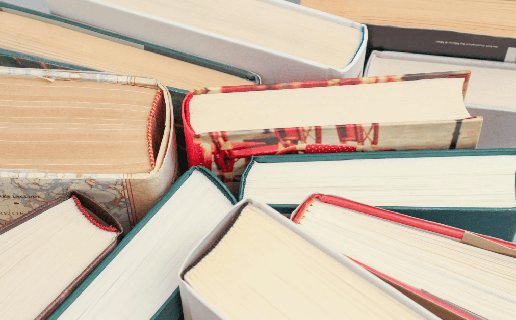 Stack of hardcover books and textbooks piled together, commonly flipped resale items found at thrift stores and library sales