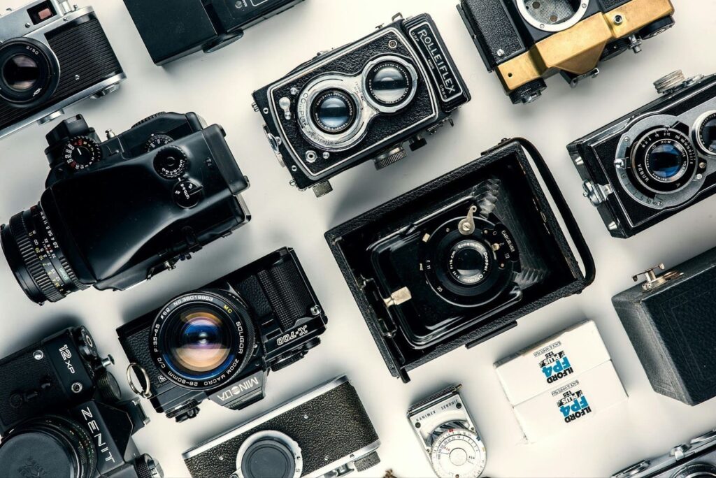 Collection of vintage film cameras and photography equipment arranged on a table, popular collectible items to flip for profit