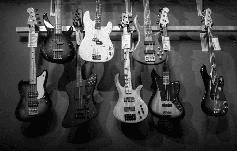 Electric bass guitars displayed on a music shop wall, instruments that often hold resale value for flipping