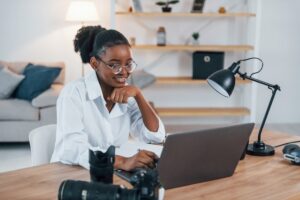 A woman sitting by the table and working on her laptop.