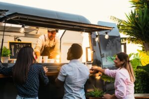 Young people buying meal from street food truck.