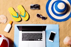 Summer vacation composition. Sandals, hat, laptop and smartphone.